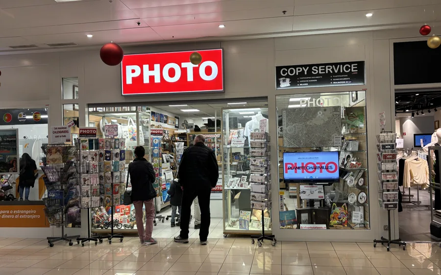La devanture de Photo Planète Charmilles dans la galerie du centre commercial, enseigne rouge PHOTO et panneau Copy Service
